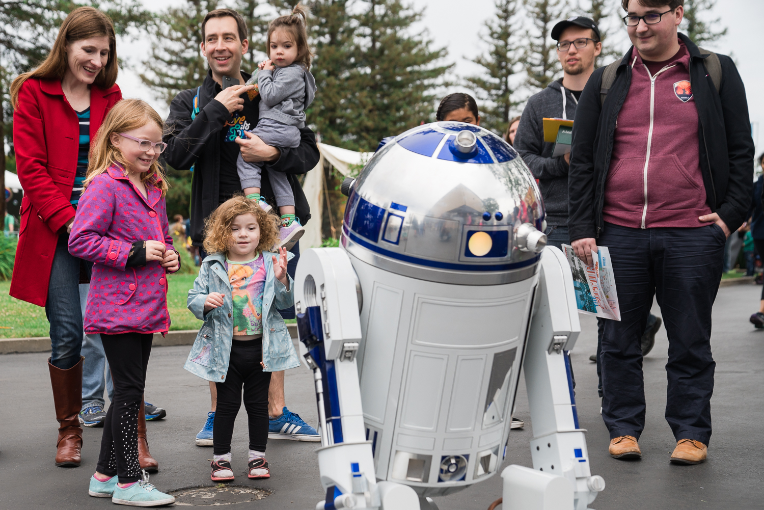 A family smiles while greeting R2D2 at Maker Faire.